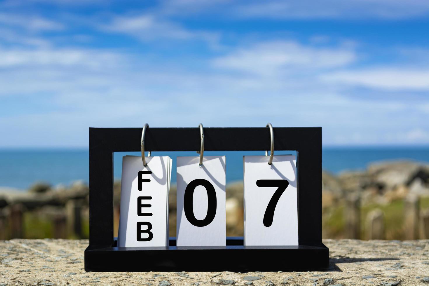 Feb 07 calendar date text on wooden frame with blurred background of ocean photo