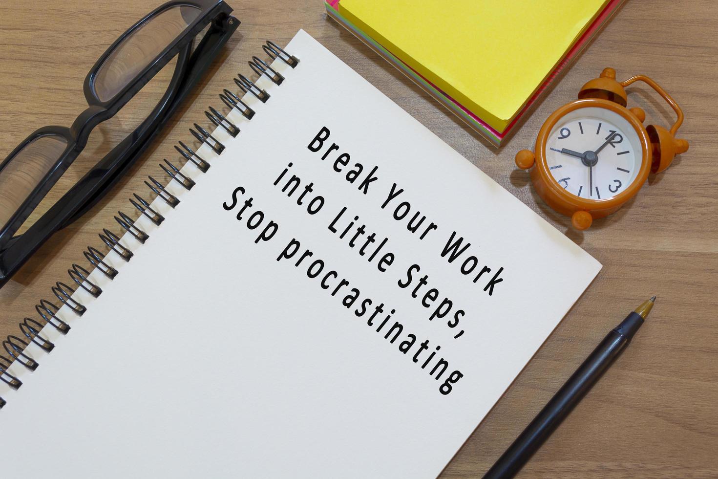 Text on notepad with alarm clock on wooden desk. Work concept photo