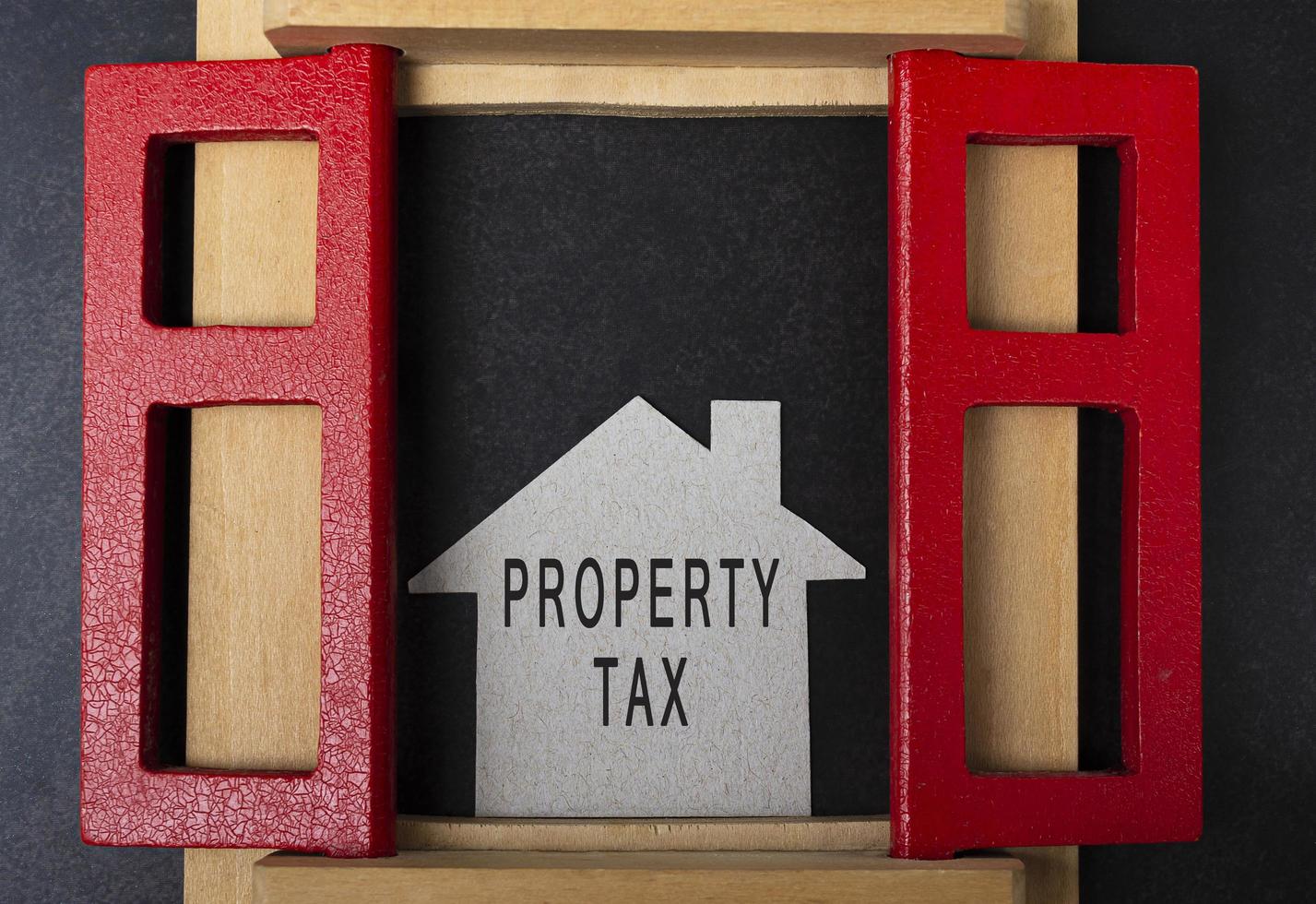 Property tax text on paper house model and in window frame on dark background photo