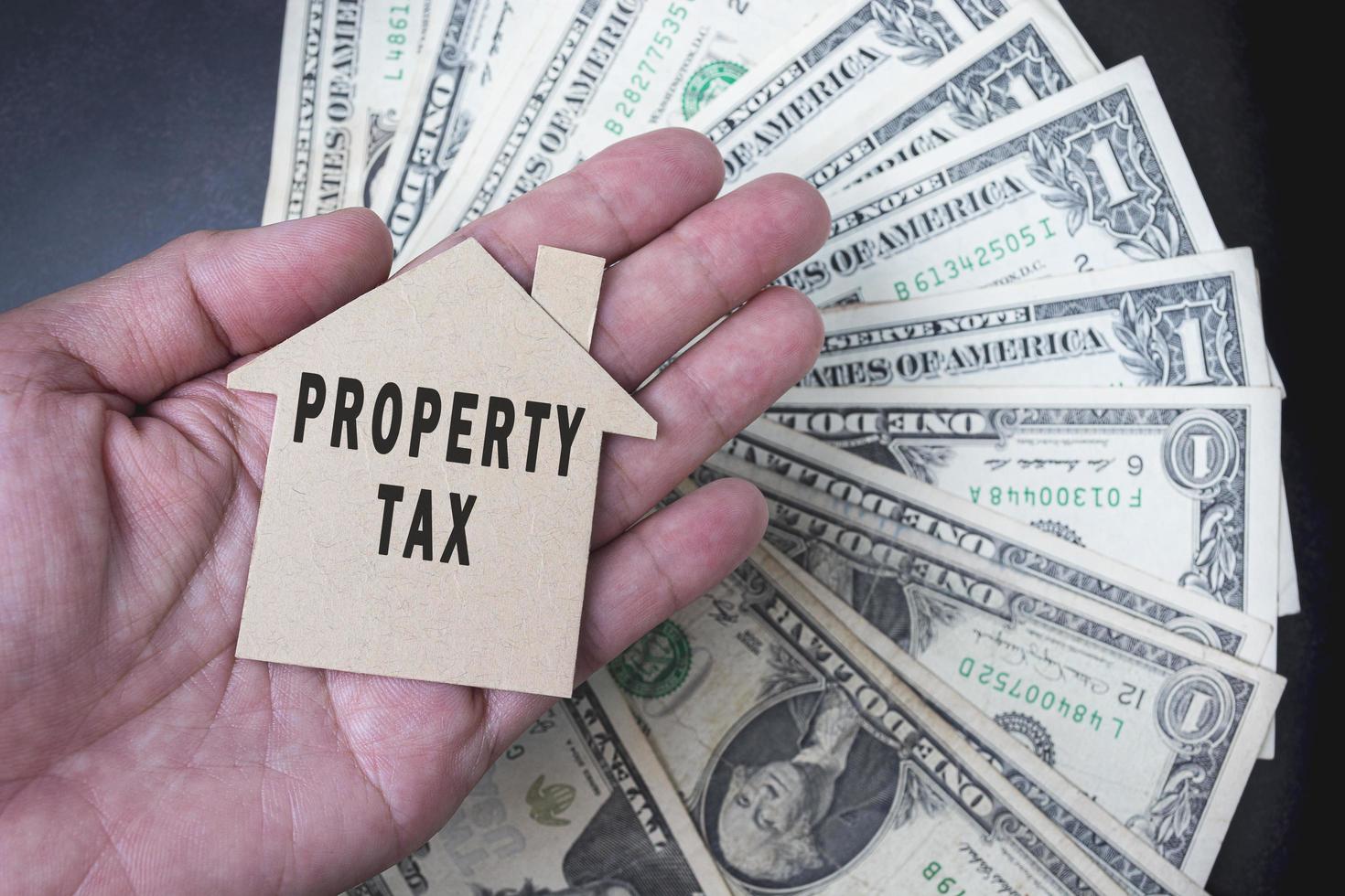 Property tax text on brown paper house model with background of dollar banknotes photo
