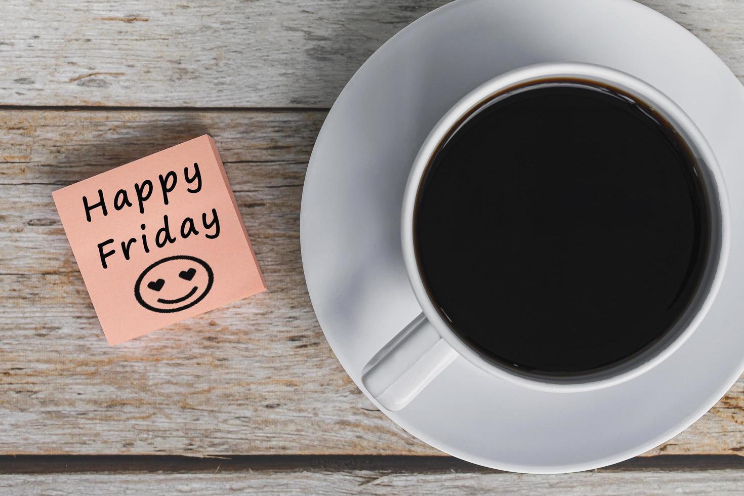 Happy friday with smile face greeting on orange sticky note with coffee cup. photo