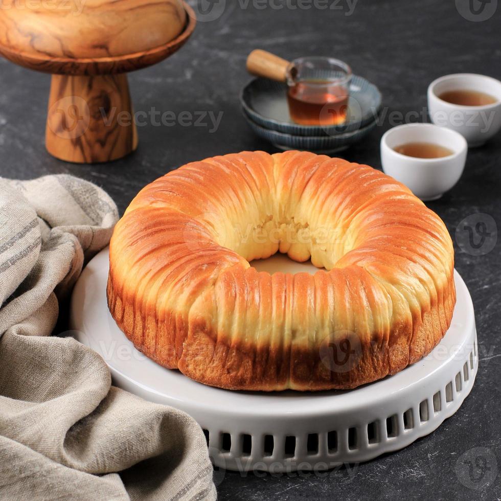 Wool Bread is Sweet Bread Dough Shaped like a Blob of Wool Thread. Filled with Chocolate and Grated Cheese. Served in White Plate, Black Table photo