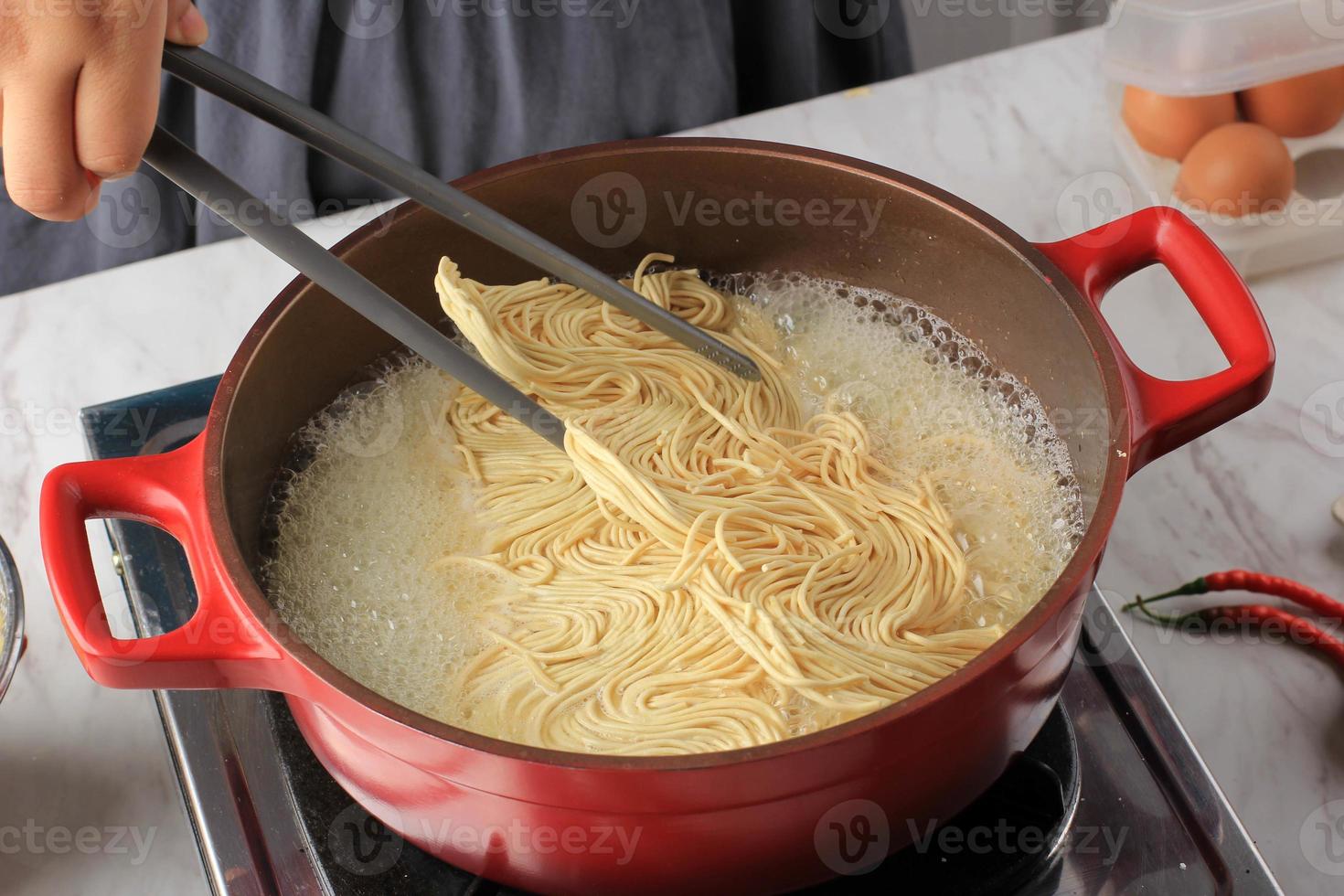 en la elaboración de fideos japoneses asiáticos, fideos secos hirviendo foto