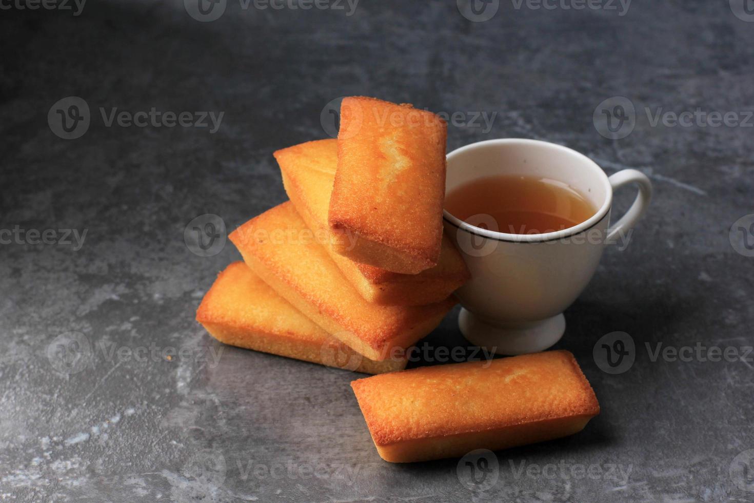 delicioso pastel financiero francés con mantequilla fresca, servido con té. copie el espacio para el texto. sobre fondo de cemento gris foto