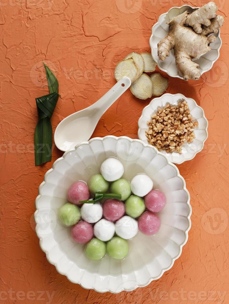 Top View Tang Yuan, Chinese Glutinous Rice Dumpling Balls with Sugar Ginger or Palm Sugar Syrup  on Orange Chinese on Black  Background for Winter Solstice New Year Festival Food. photo