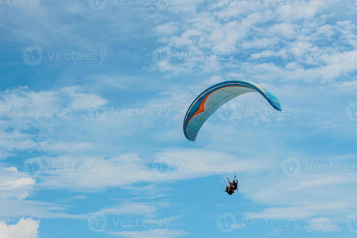 Paraglider tandem flying over the sea with blue water and beach in bright sunny day. photo