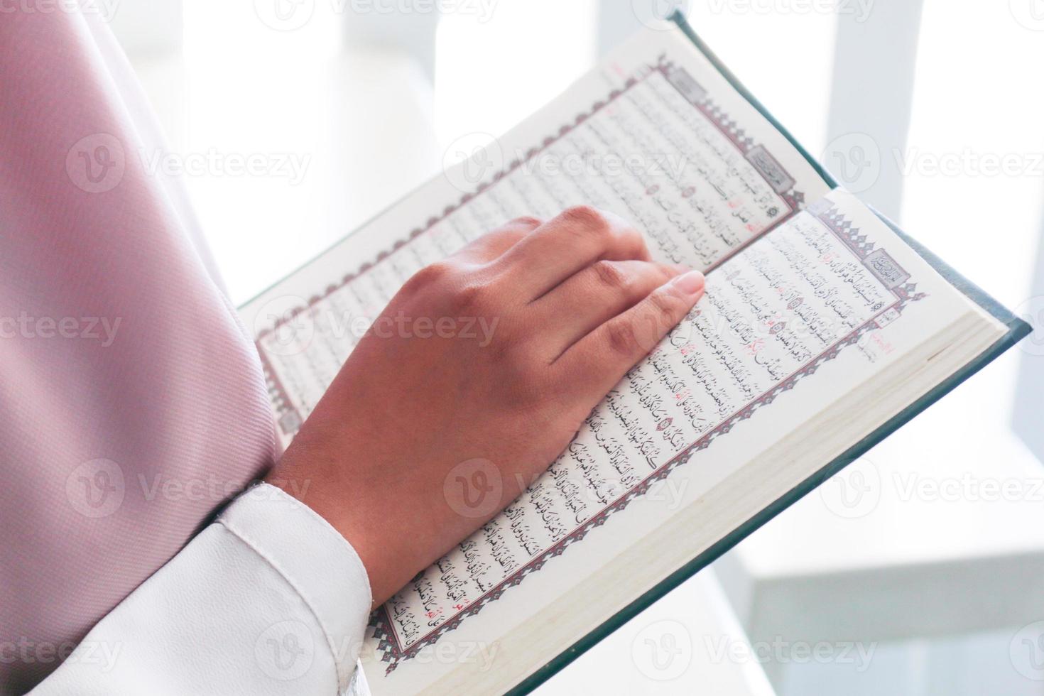 Close up of hand when reading the Holy Quran at the mosque. Selective focus photo