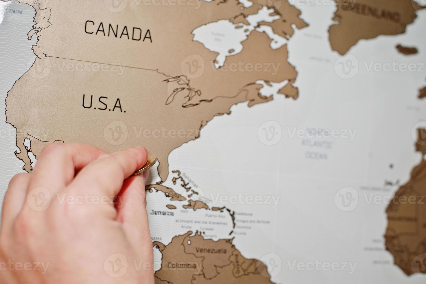 Scratch travel map of the world. Hand of man erase USA with coin. photo