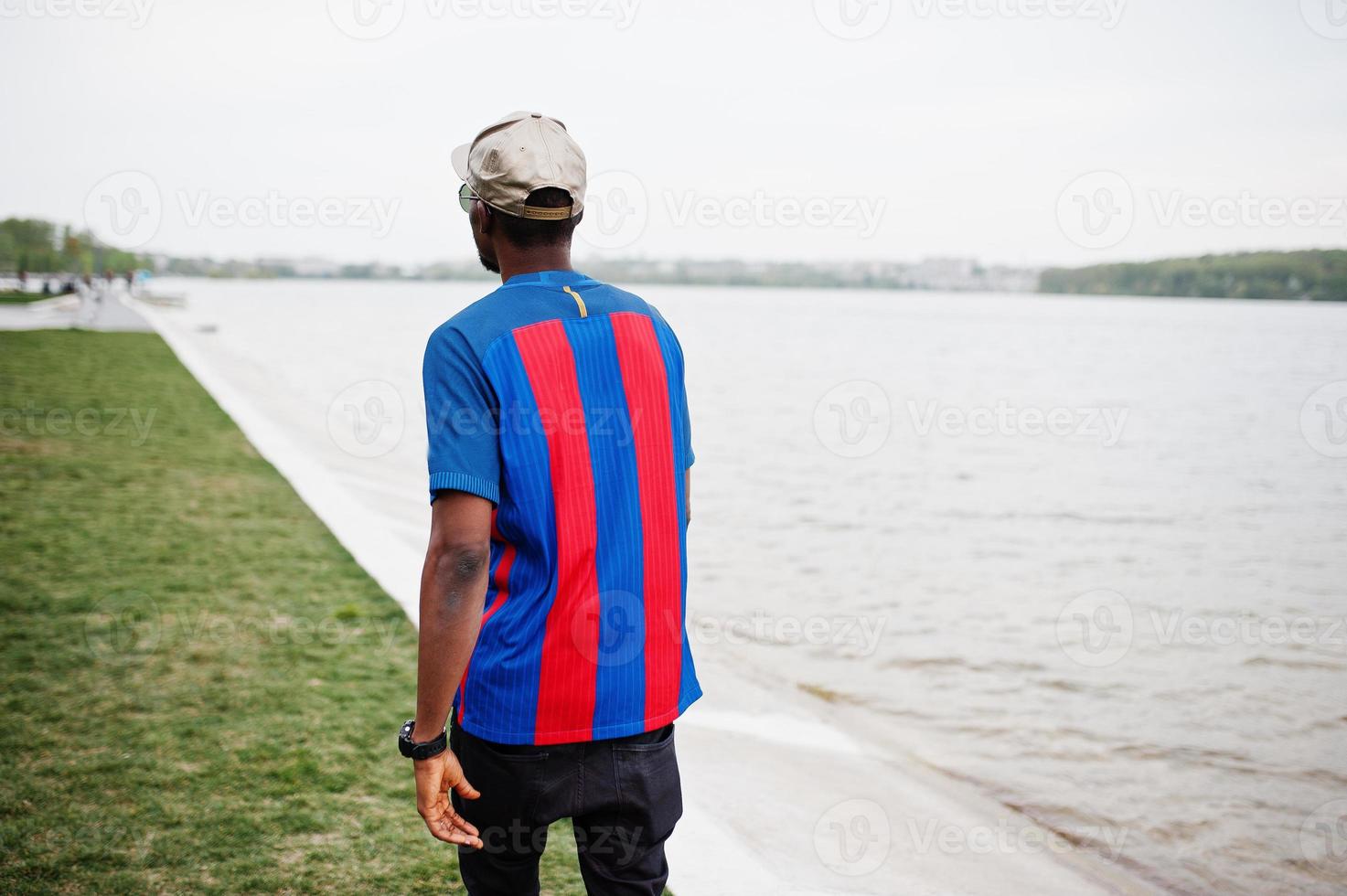 Stylish african american boy wear at cap, football t-shirt and sunglasses. Black sports man portrait. photo