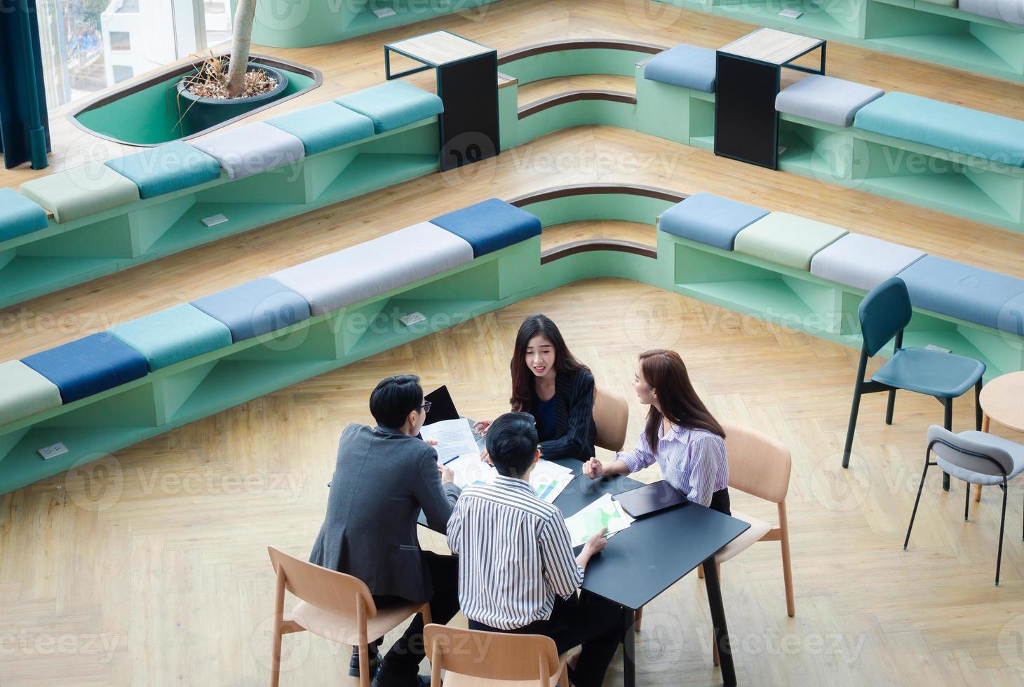 grupo de jóvenes equipos de negocios discuten algo mientras se sientan juntos en la mesa del espacio de trabajo conjunto, planifican la estrategia y la lluvia de ideas, los colegas piensan en el concepto foto