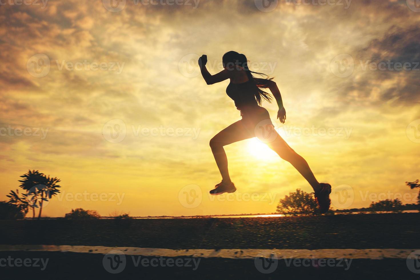 Silhouette of young woman start running at road track. Fit runner fitness runner during outdoor workout with sunset background. Selected focus photo