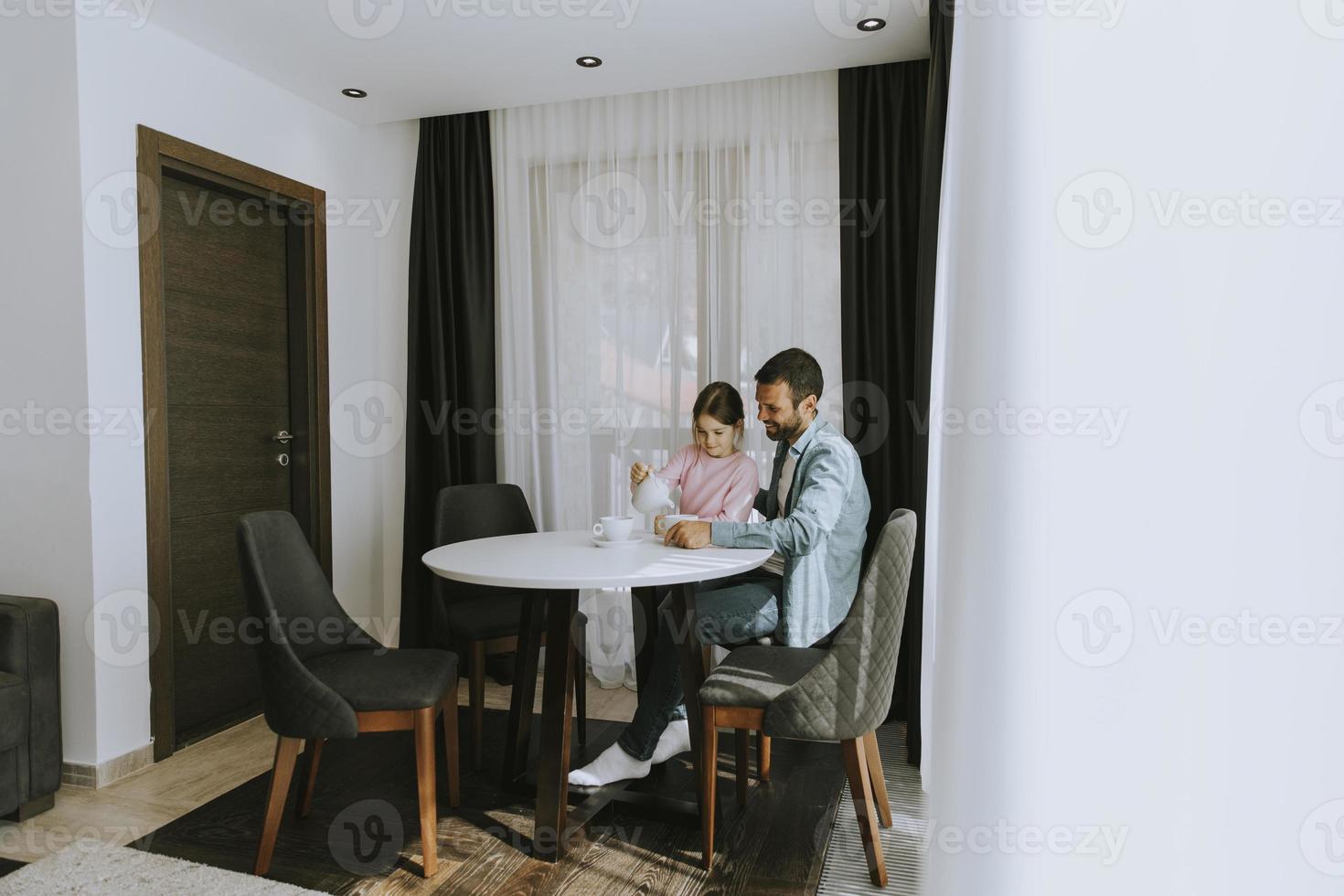 Father and daughter drinking tea together at the room photo