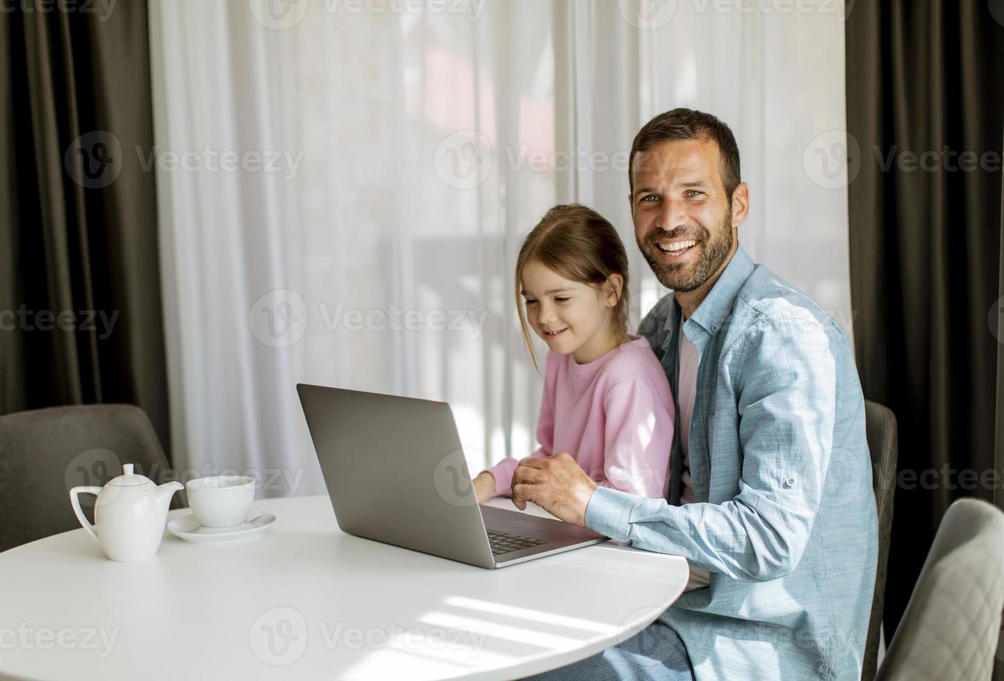 Father and daughter using laptop computer together photo