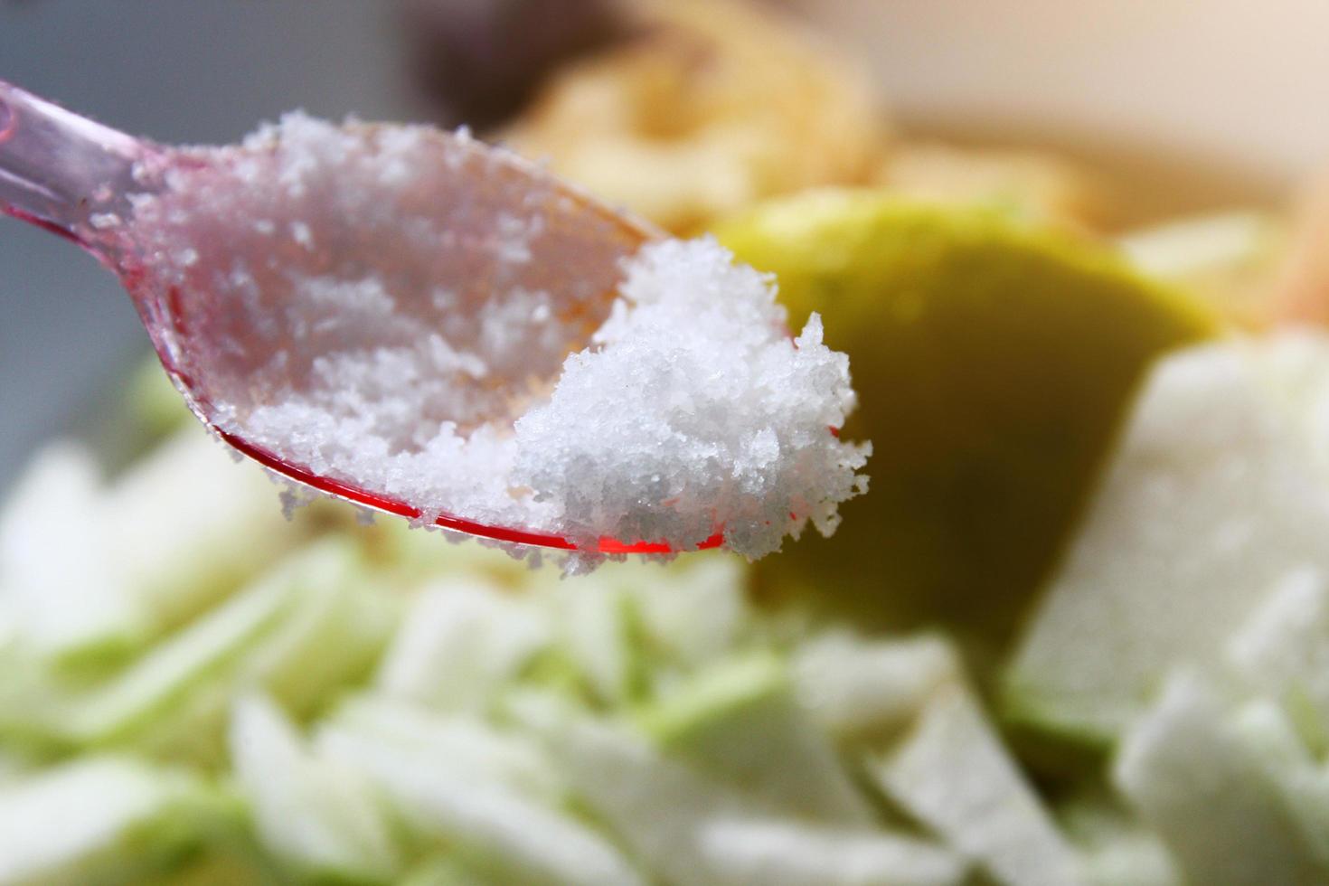 Sea salt in a red plastic spoon photo