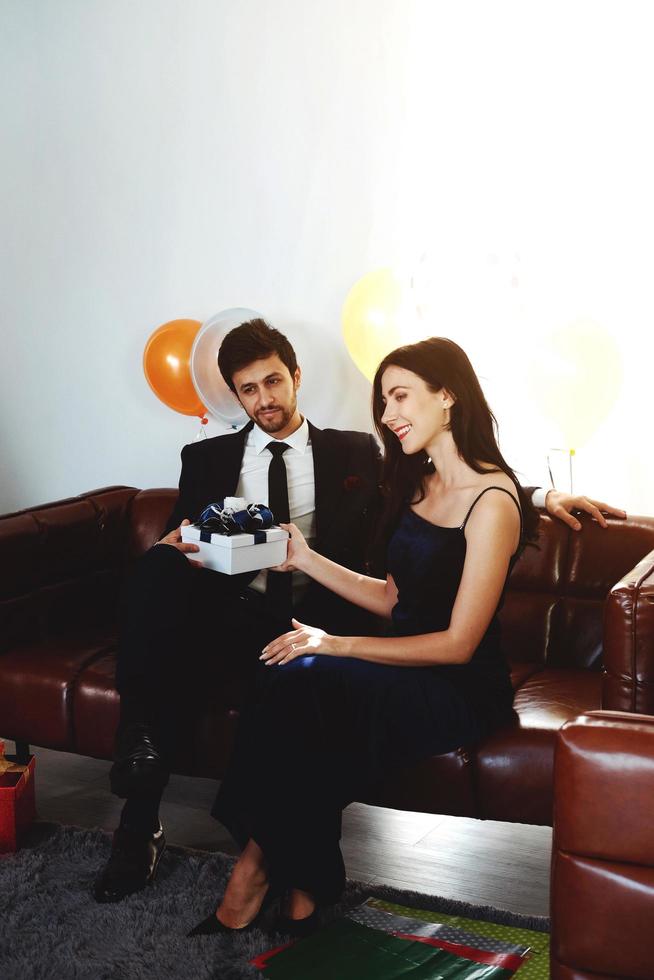 Sweet couple Love smile and spending Romantic christmas time and celebrating new year eve on Brown Sofa decoration with Christmas tree, colorful balloon and Gift Boxes in Living room at home photo