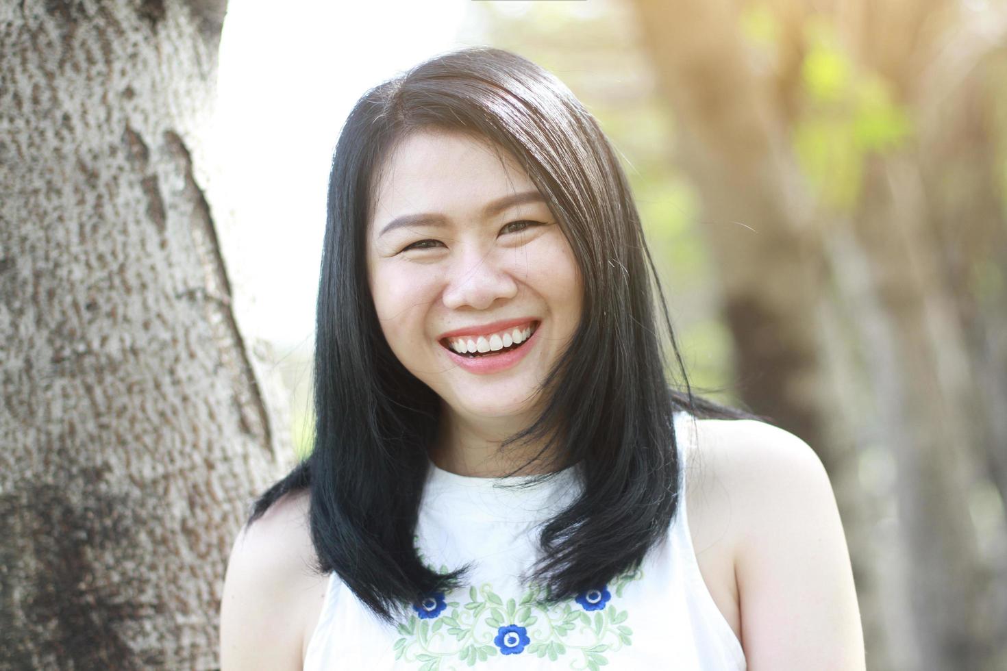 Beautiful asian woman in white dress happy and big smile with natural sunlight in the park. Thai girl or Chinese Girl enjoy on holiday in garden photo