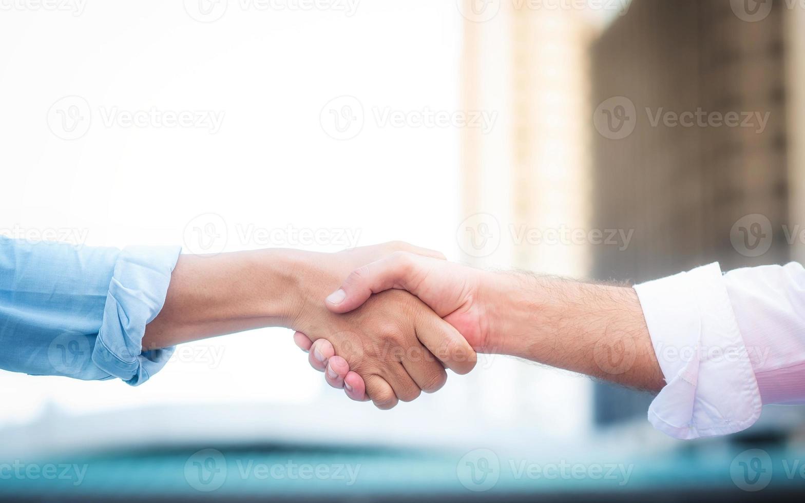 Two roll up shirt sleeves businessman shaking hands with blur building background, successful business collaboration and teamwork,Team agreement in hands gesture communication, friendly and informal photo