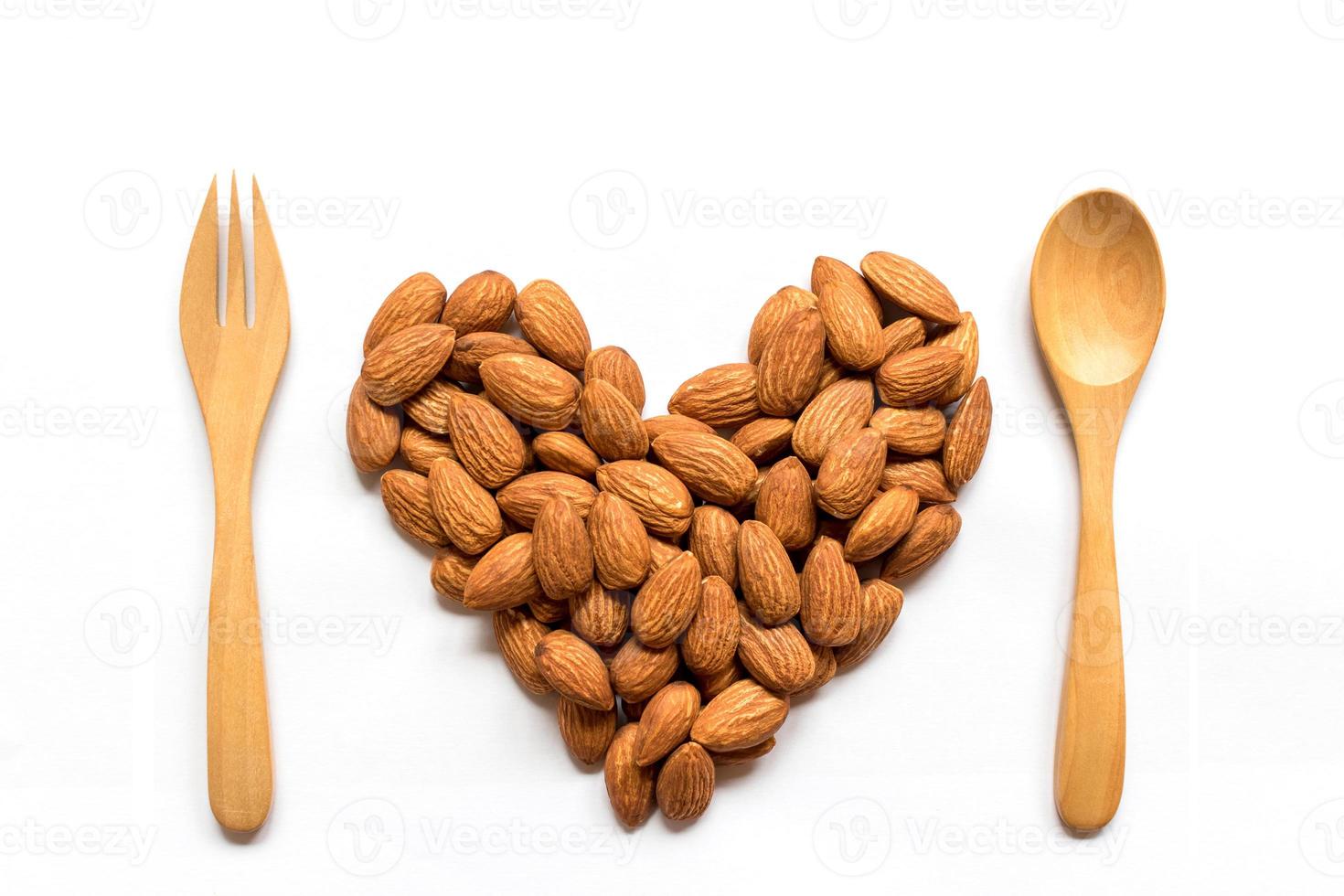 Almonds heart shape pattern with wood fork and spoon isolated on white background with blank.Love valentine's day concept. photo