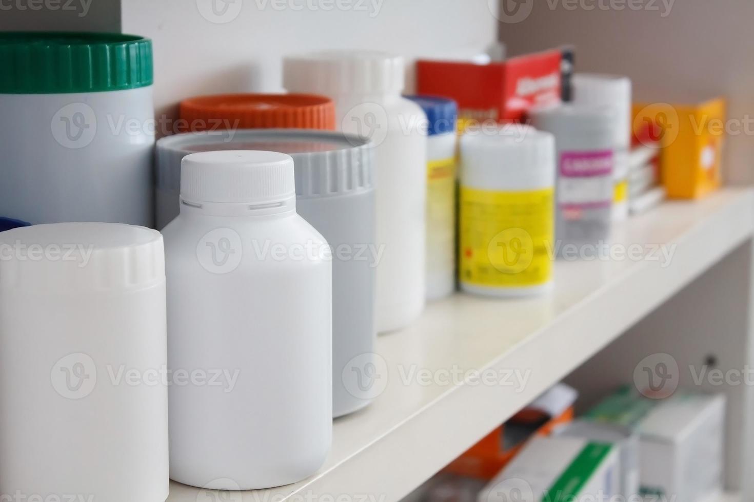 Frascos de pastillas dispuestas en estante en farmacia foto