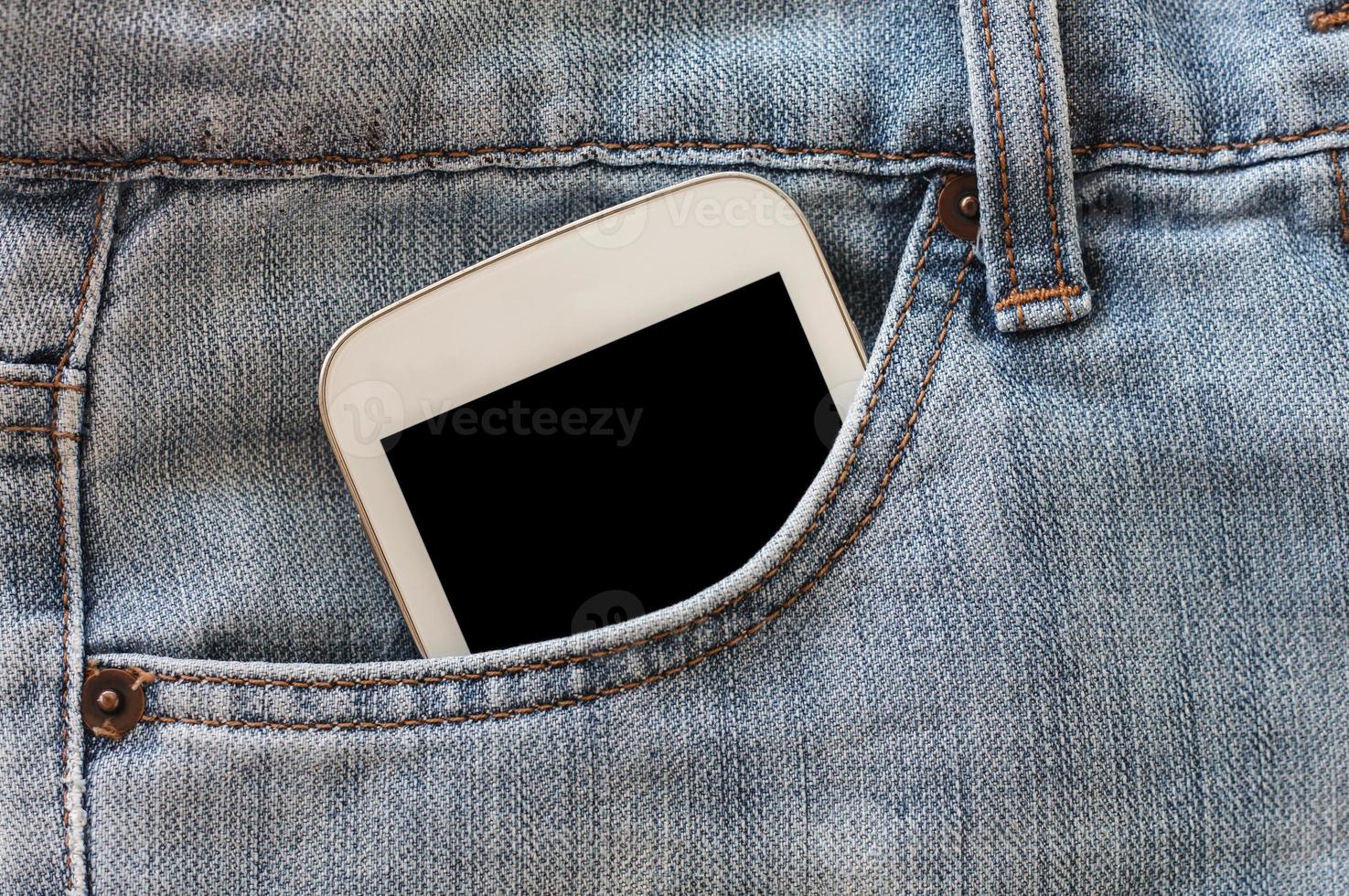 teléfono móvil en el bolsillo de los jeans con pantalla negra foto