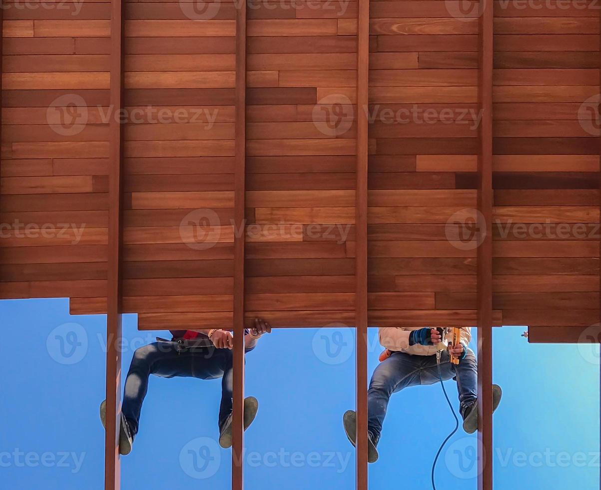 dos trabajadores están instalando material de techo de teca de madera en el sitio de construcción de casas tropicales, enfoque selectivo, espacio de copia. foto