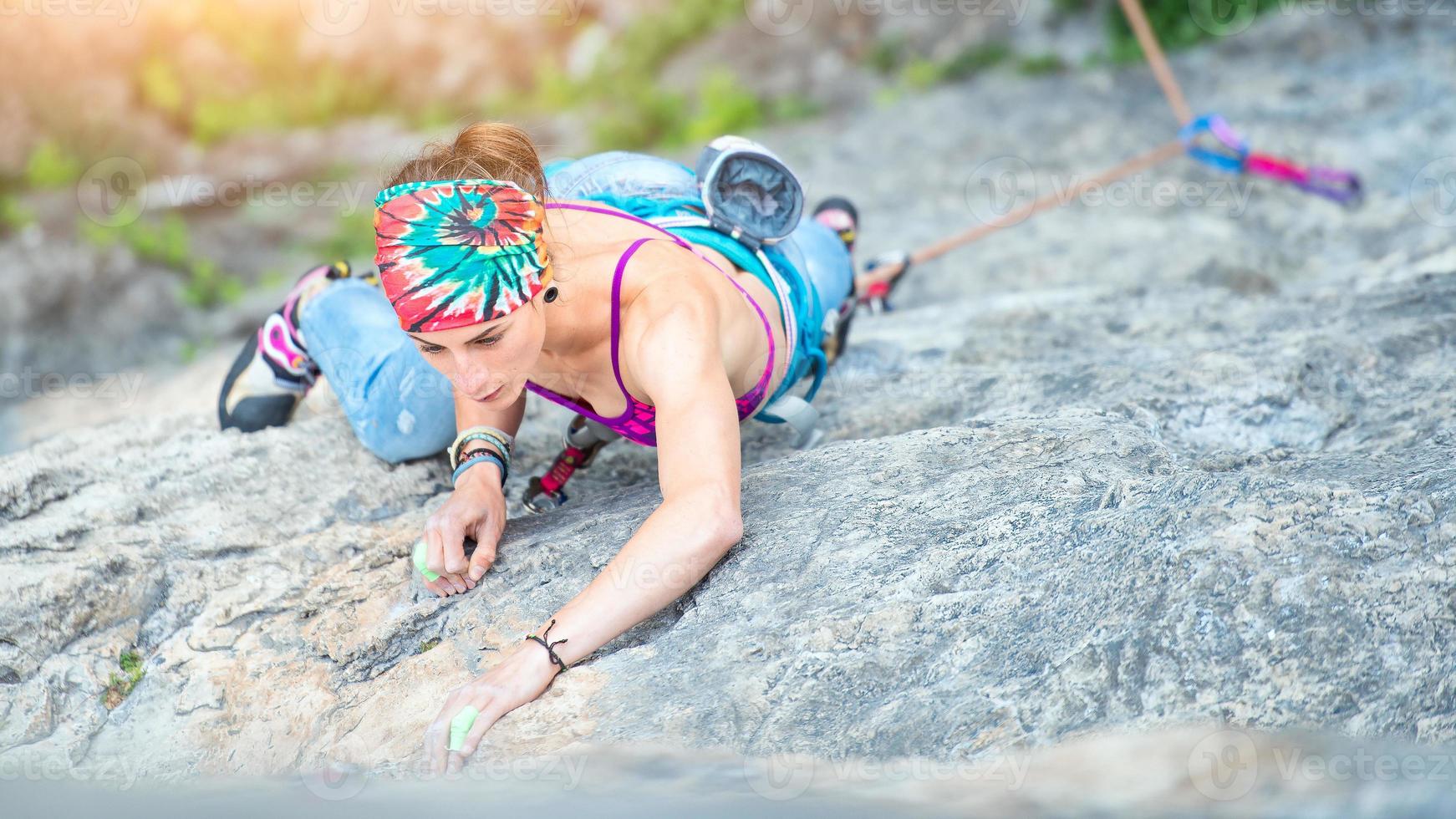 chica concentrada en un pasaje de escalada en roca foto