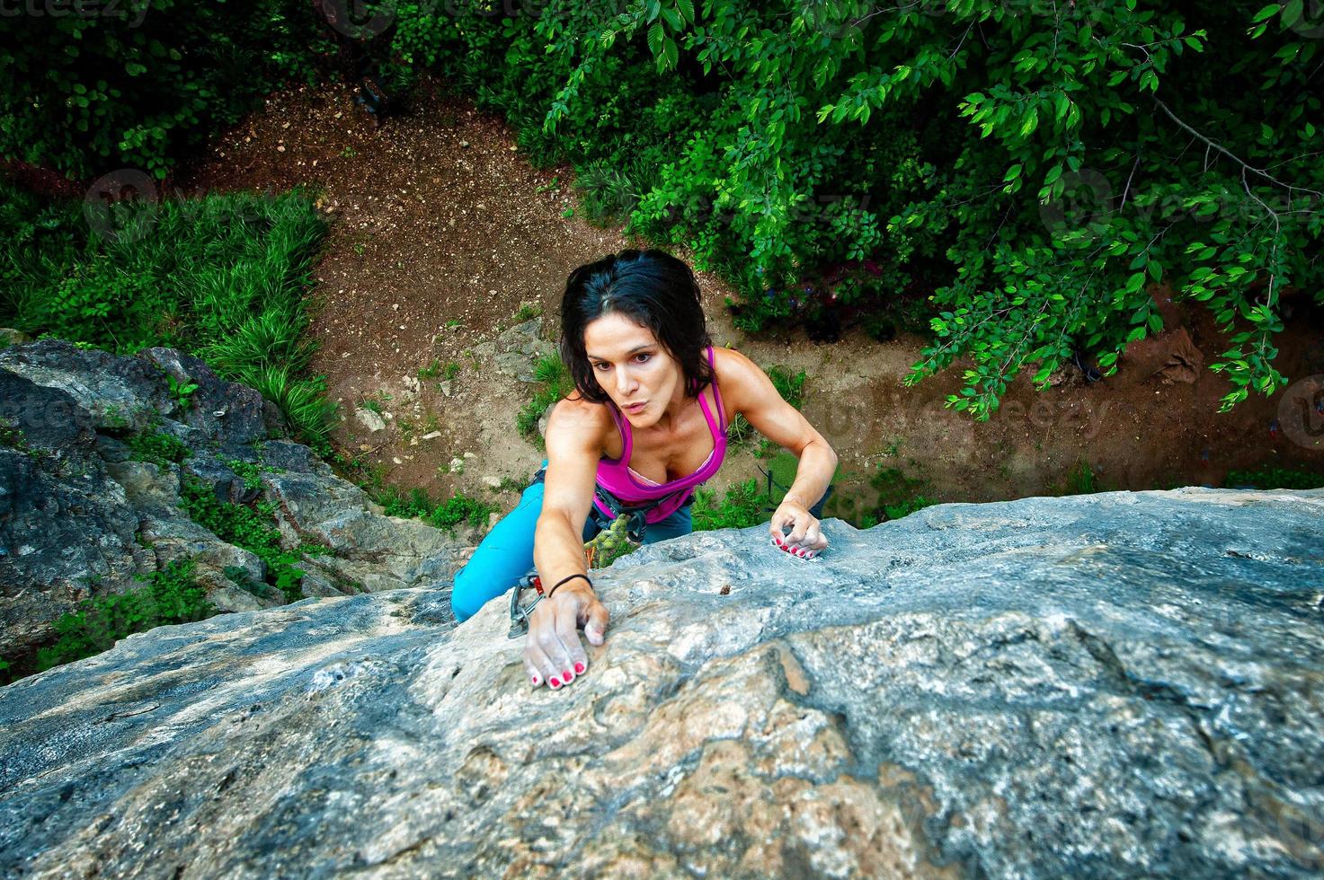 Beautiful dark-haired girl climbs on rock photo