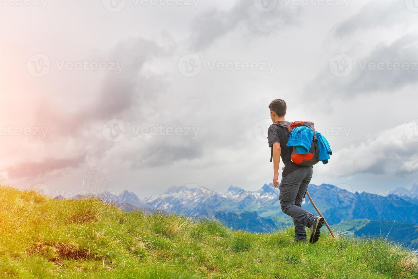 Boy walking in the mountains with his stick in the meadows photo