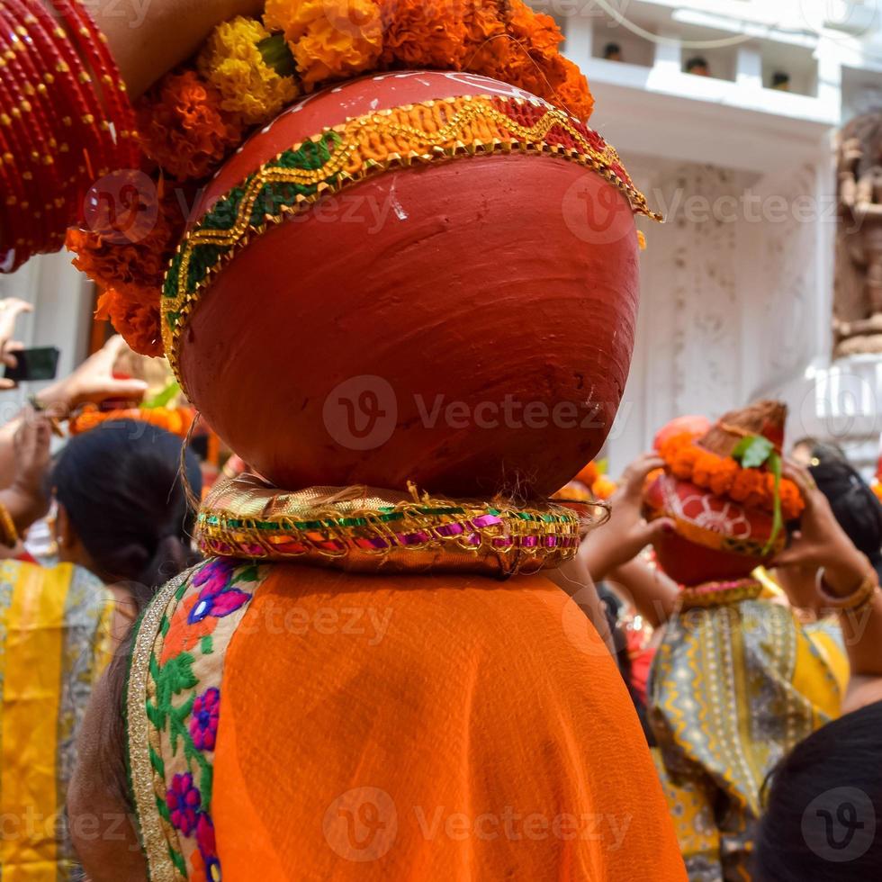 mujeres con kalash en la cabeza durante el templo jagannath mangal kalash yatra, devotos hindúes indios llevan ollas de barro que contienen agua sagrada con un coco encima foto