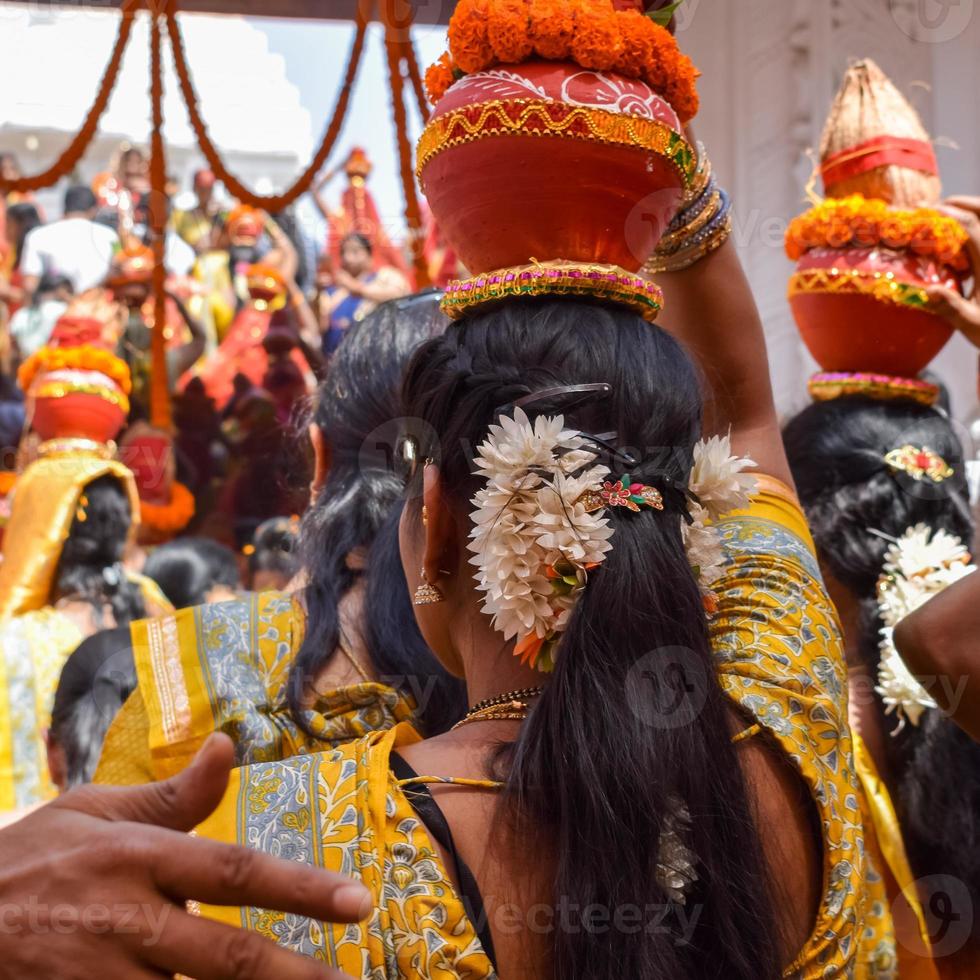 mujeres con kalash en la cabeza durante el templo jagannath mangal kalash yatra, devotos hindúes indios llevan ollas de barro que contienen agua sagrada con un coco encima foto