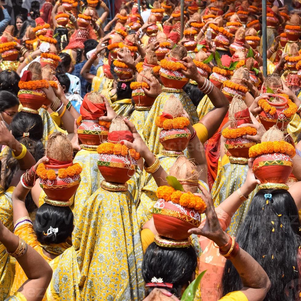 mujeres con kalash en la cabeza durante el templo jagannath mangal kalash yatra, devotos hindúes indios llevan ollas de barro que contienen agua sagrada con un coco encima foto