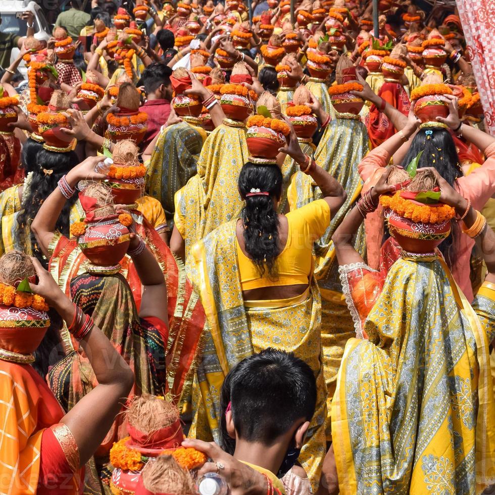 mujeres con kalash en la cabeza durante el templo jagannath mangal kalash yatra, devotos hindúes indios llevan ollas de barro que contienen agua sagrada con un coco encima foto