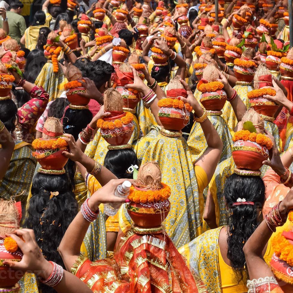 mujeres con kalash en la cabeza durante el templo jagannath mangal kalash yatra, devotos hindúes indios llevan ollas de barro que contienen agua sagrada con un coco encima foto