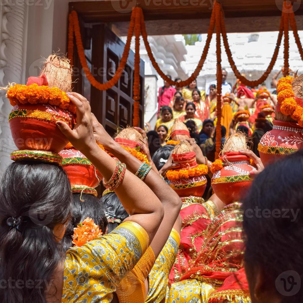 mujeres con kalash en la cabeza durante el templo jagannath mangal kalash yatra, devotos hindúes indios llevan ollas de barro que contienen agua sagrada con un coco encima foto