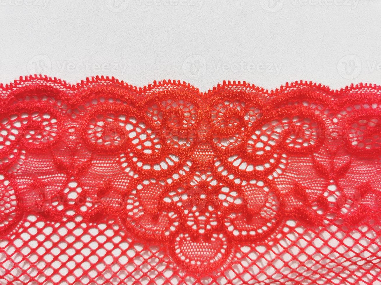 Red lace on a white background. Lingerie element. Textured openwork pattern. photo
