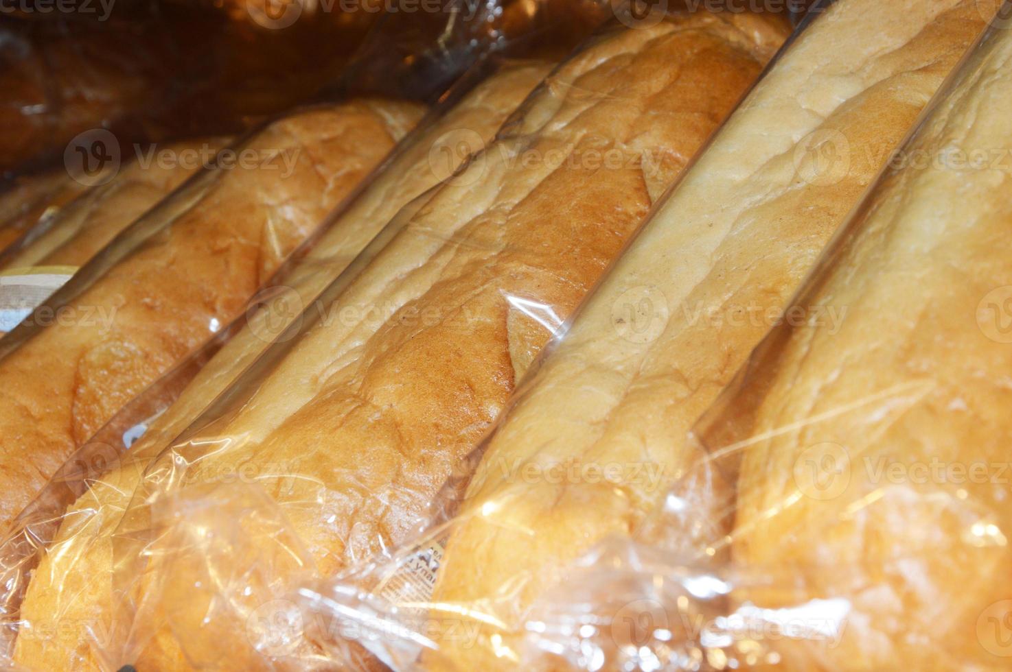 Loaves of white bread in plastic bags on the counter of the store, packaged for sale. photo