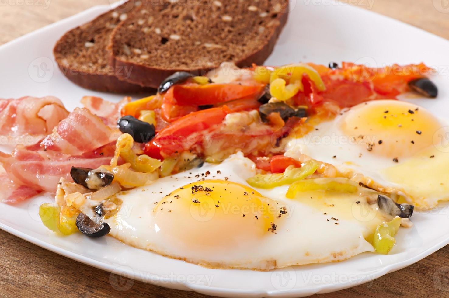 Breakfast - fried eggs with bacon, tomatoes, olives and slices of cheese photo