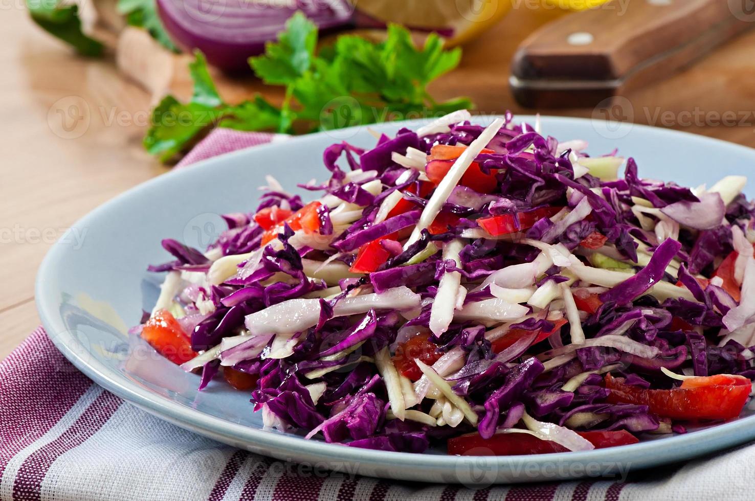 ensalada de col roja y blanca y pimiento rojo dulce, sazonada con jugo de limón y aceite de oliva en un tazón de madera foto