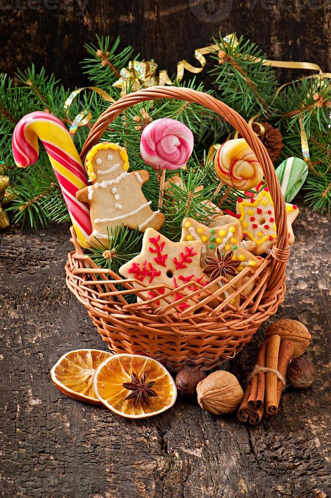 galletas de jengibre de navidad y piruletas en una canasta sobre fondo de madera vieja foto