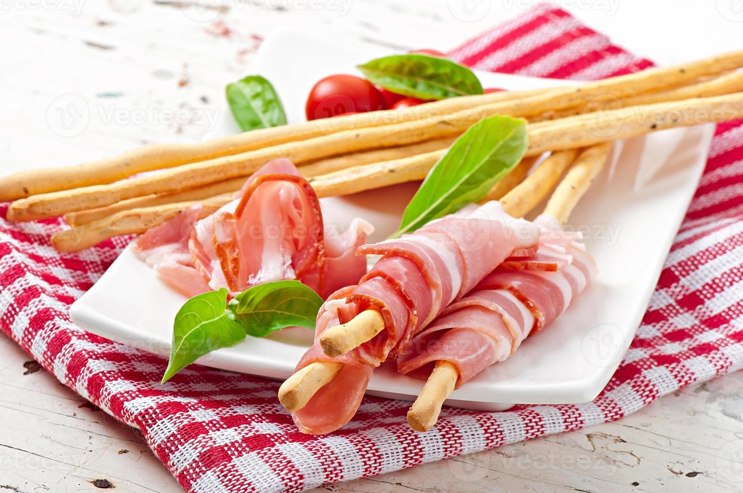 Grissini bread sticks with ham, tomato and basil photo