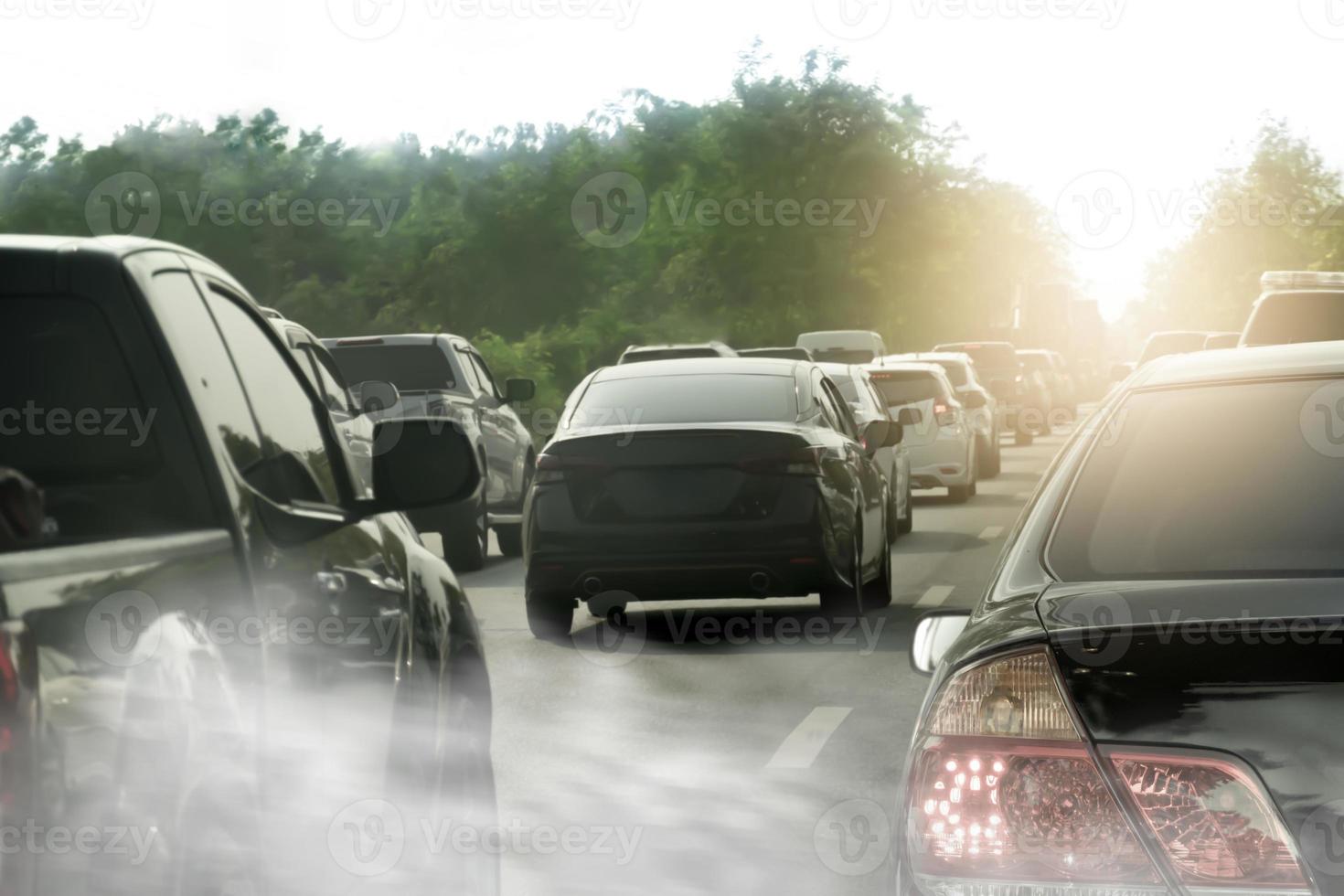 Transport abstract background of cars on the road with queuing during traffic jams. Blurred image of smoke in front. Background image of dense green trees on the side of the road under a bright sky. photo