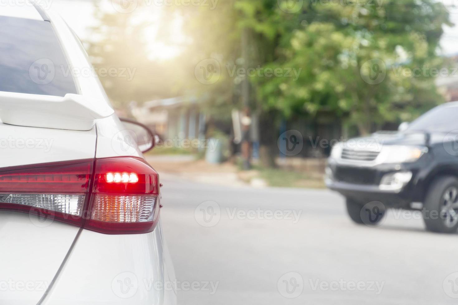 Rear side of white car driving on the asphalt road. Cars from the side are about to turn. And grees trees in the upcountry. photo