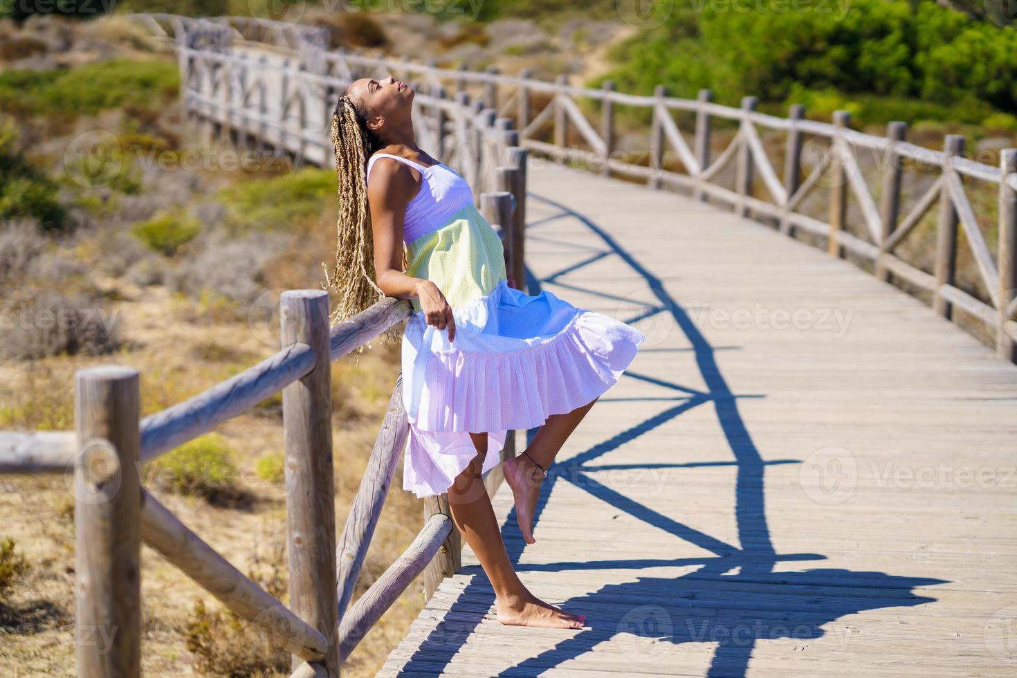 mujer africana con un hermoso vestido en un paseo marítimo en la playa. foto