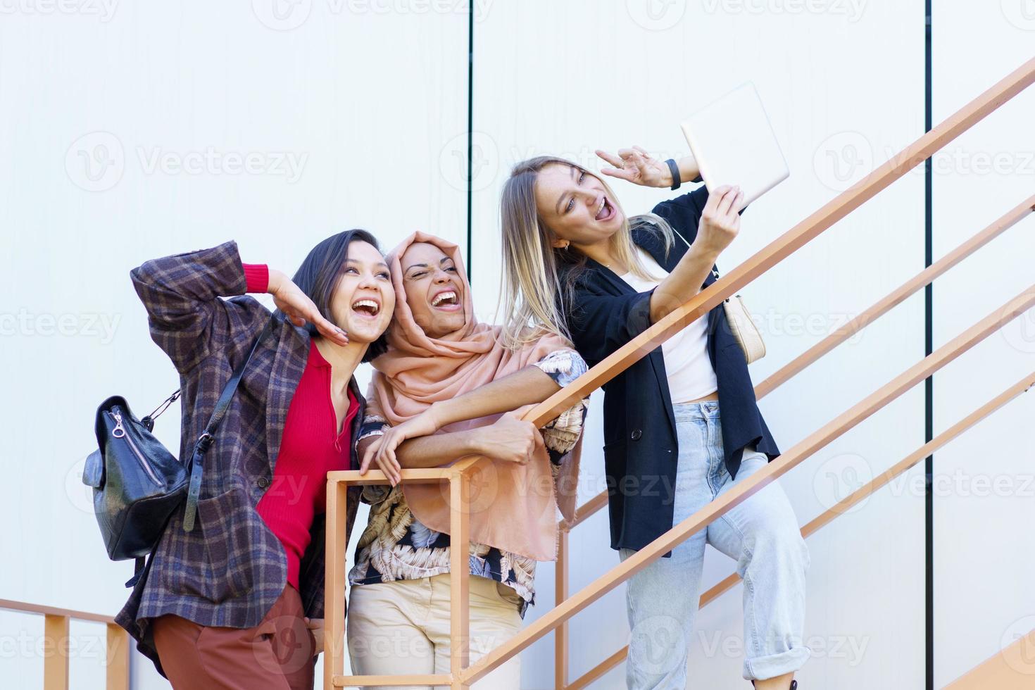 emocionados jóvenes multiétnicos millennials sonriendo y tomando selfie en tableta foto