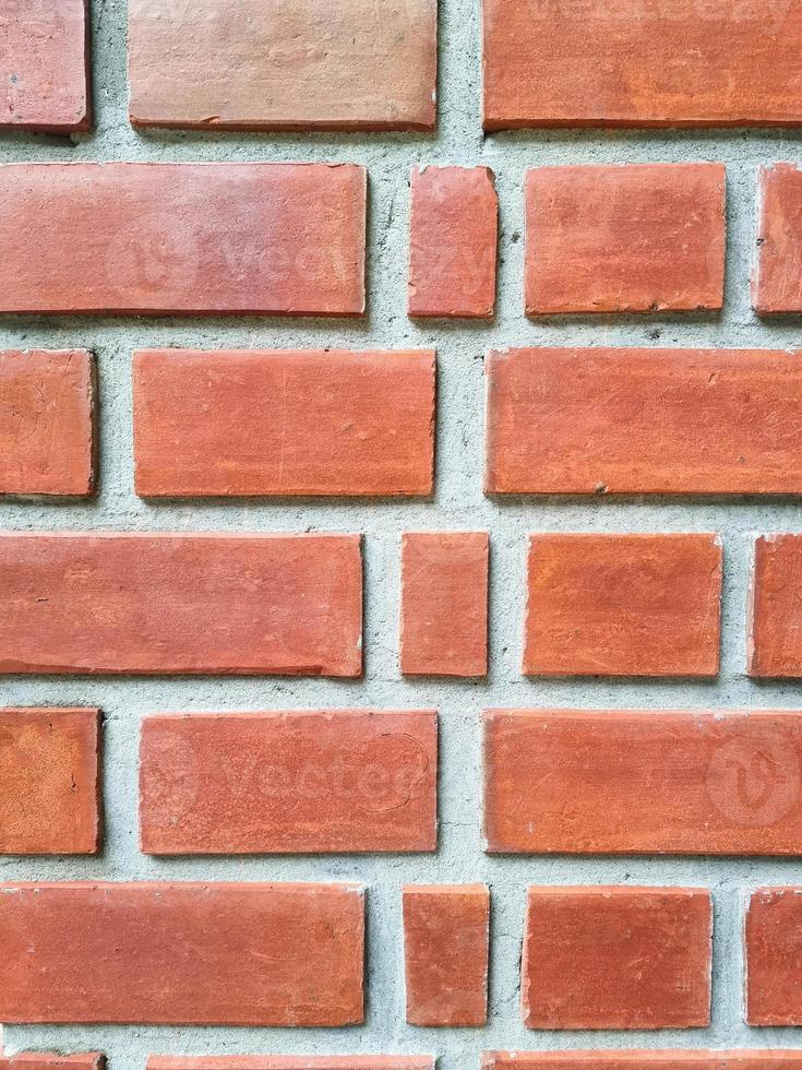 bloque de ladrillo cuadrado naranja en la pared de cemento con textura y fondo. Interiores fuertes casa edificio imagen vertical foto