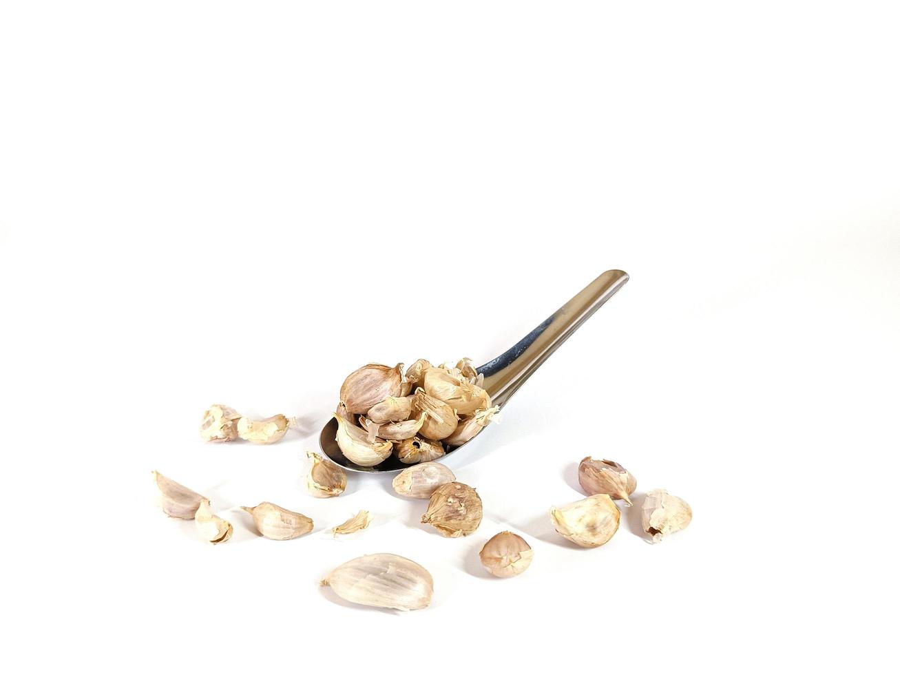 old garlic on stainless steel spoon on a white background photo