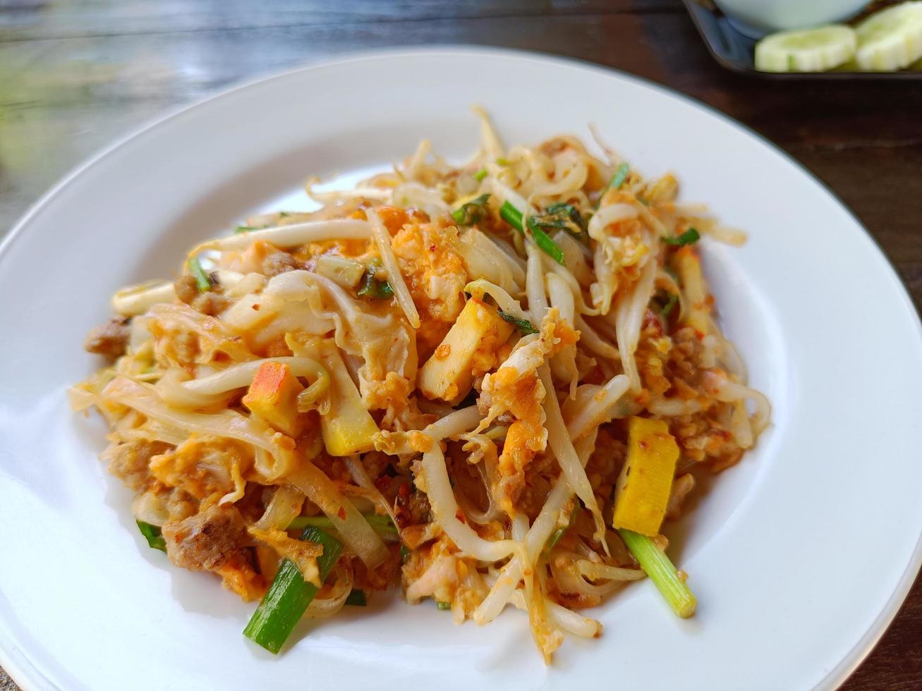 Pad Thai with minced pork and tofu on a white plate on the brown table popular Thai food photo