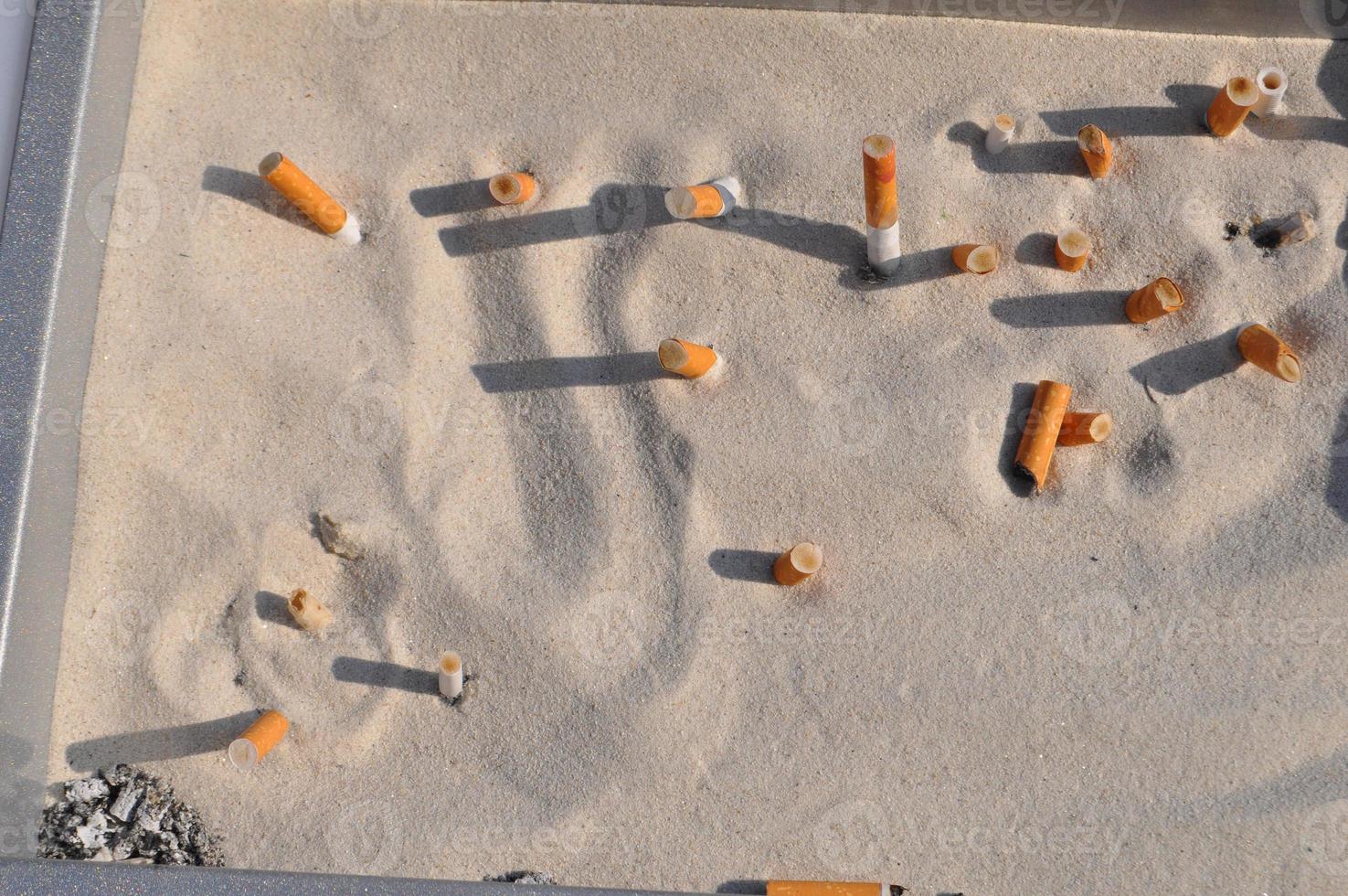 colillas de cigarro en la arena foto