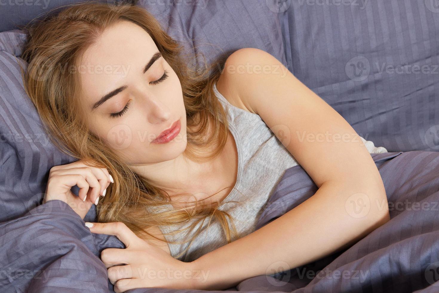 hermosa chica duerme en el dormitorio. mujer dormida en la cama de cerca. joven hermosa mujer durmiendo. retrato de la hermosa joven durmiendo en la cama oscura. foto