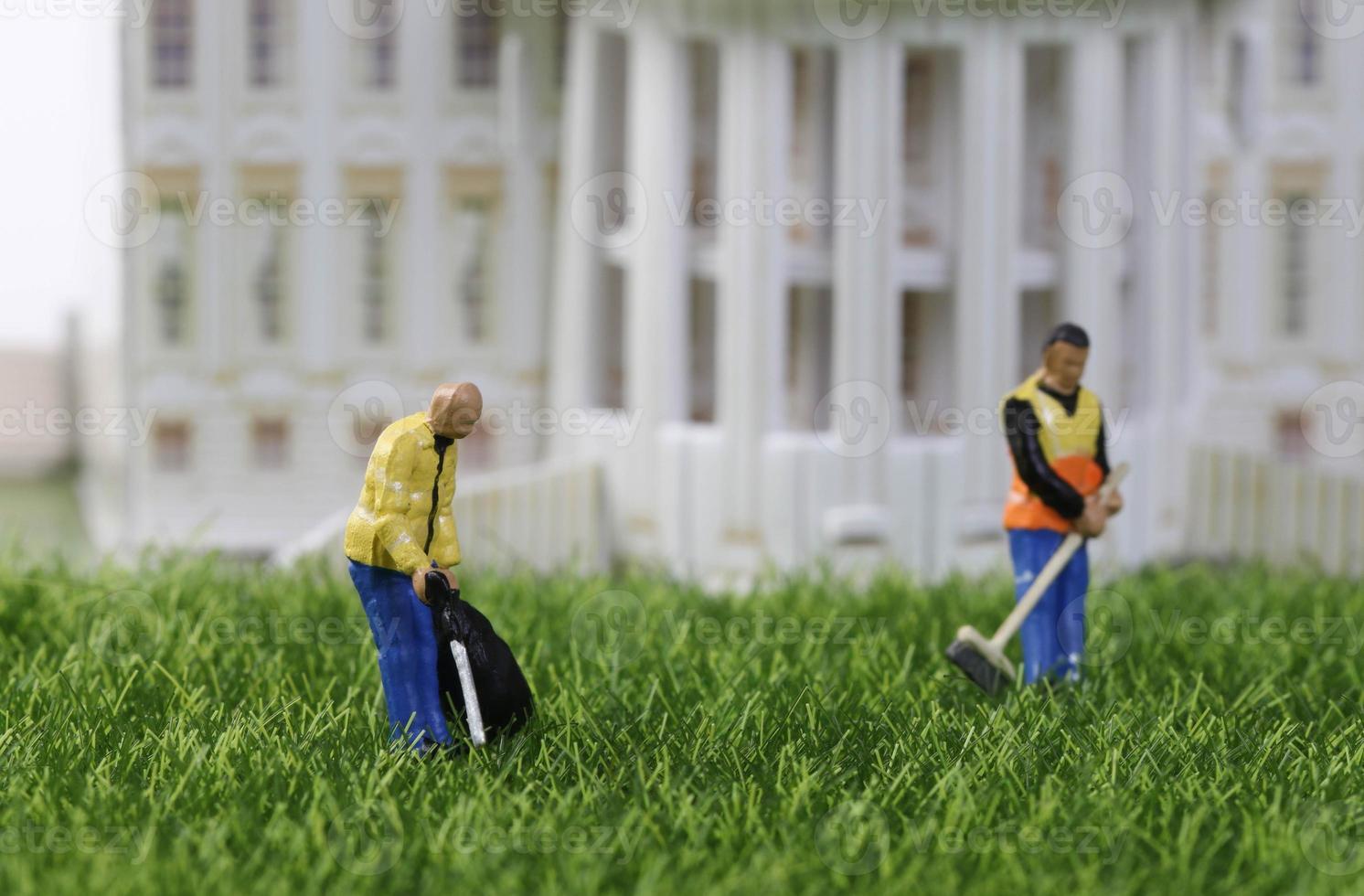 Cleaning workers standing on the grass in front of building photo